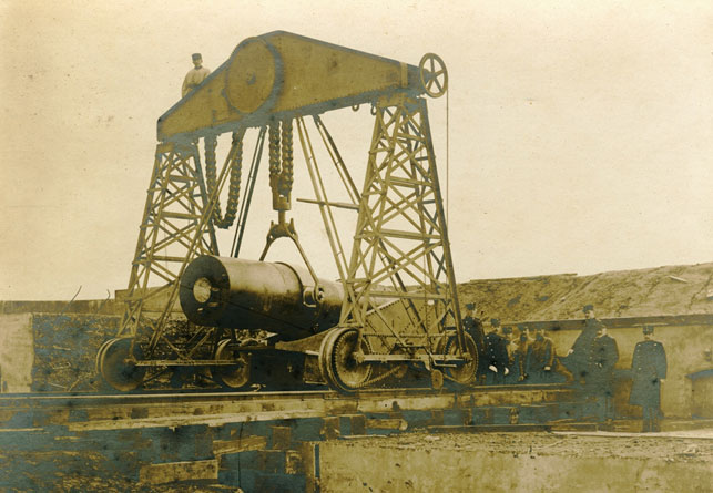 Opstillingen af en ud af 12 styk 290 mm howitzers på Charlottenlund Fort, et kystbatteri opført 1883-86 og nedlagt i 1932. Fortet var en del af et dansk forsvar, hvor man på forhånd havde opgivet Jylland, Fyn og Sjælland, og koncentrerede sig om at befæste og forsvare København. En idé som Aage Westenholz vendte sig stærkt i mod. Wikipedia.