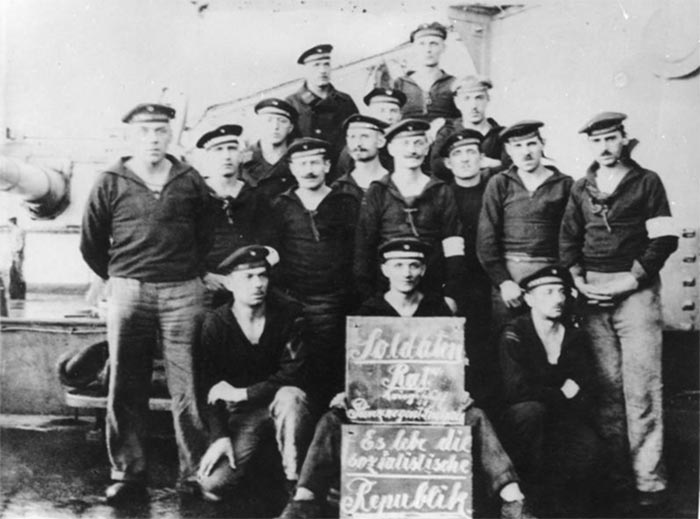 Revolutionære matroser i Kiel (Wikipedia). På skiltet står: ”Soldaterråd krigsskib prinsregent Luitpold. Leve den socialistiske republik”.